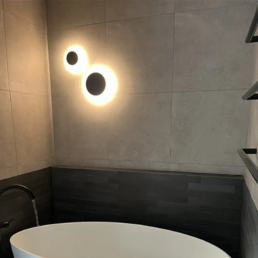 Freestanding bath with a wall light and dark tiles