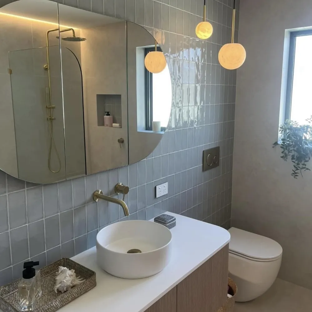 Bathroom vanity with a curved mirror and pendant lights